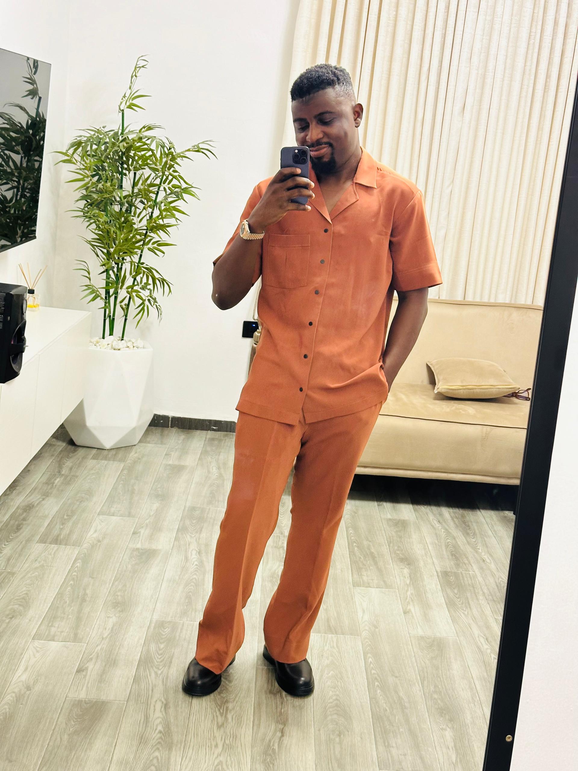 Desmond in an orange outfit taking a mirror photo